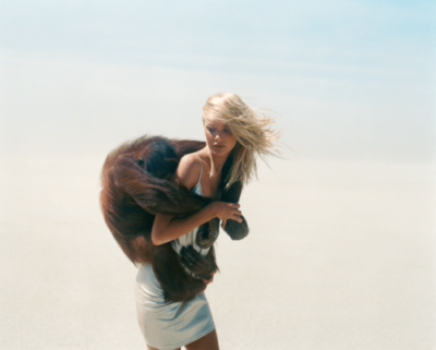 Michel Comte's Beauty and Beast series, model in silver dress carrying a monkey on her back in the desert