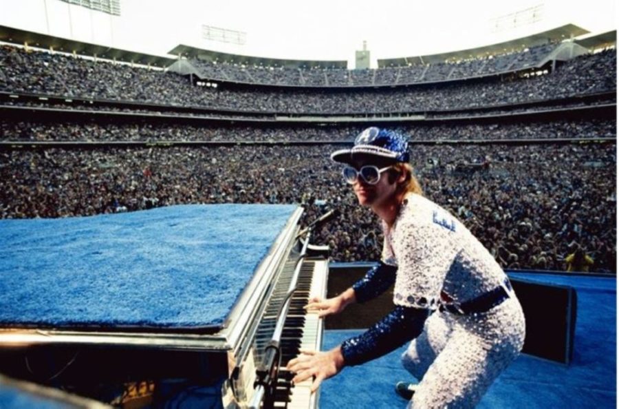 Elton John, Dodgers Stadium - Colour. 1975 by Terry O'Neill, the singer playing the piano in blue and yellow crystal suit
