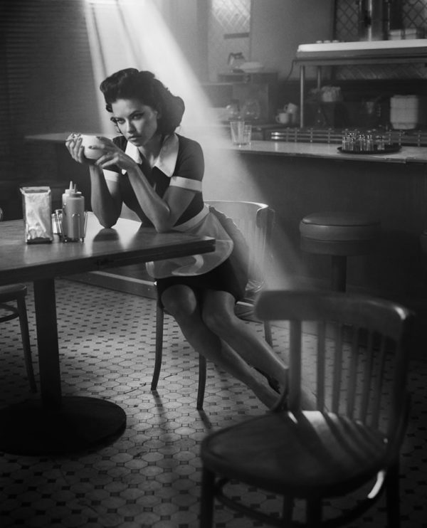 Adriana Lima by Vincent Peters, the model in waitress attire and a cup of coffee sitting in a diner