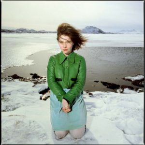 Bjork 1988 by Timothy white, the singer in green leather jacket sitting in the snow by a beach