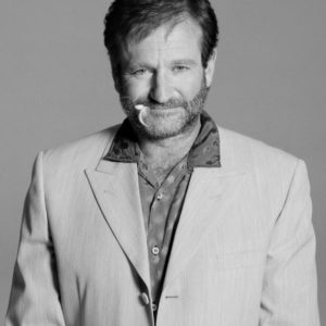 Robin Williams by Timothy white, black and white portrait of the actor in a light suit with a feather in his mouth
