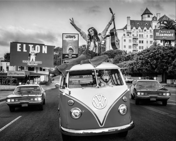 Summer of '75 in b&w by David Yarrow, VW Bus driven by Dog while a model with guitar is sitting on top