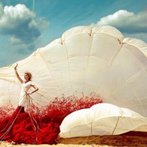 Parachute dress by Kristian Schuller, model in red and white dress with parachute on the beach