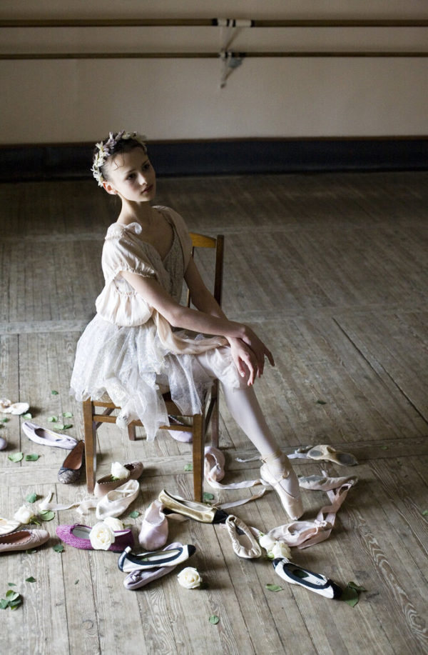 Christina Shapran by Arthur Elgort, ballerina in tutu and flowercrown sitting on a chair between shoes