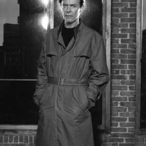 David Bowie New York by Markus Klinko, the singer in trenchcoat in front of window and brick wall