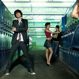Tommy Lee, the locker room by Markus Klinko, the Rockstar in a Suit, standing between blue lockers with three girls