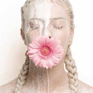 "Flower Girl, 2016" by Sylvie Blum, part of the Space Age Series. Fine Art Print, colour, showing woman with flower in mouth, braided hair and eyes closed, milk running across her face