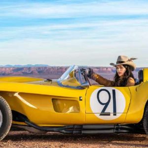 The Girl with the Feathered Hat, Monument Valley, Utah 2023, color by David Yarrow - Girl with a cowboy hat sitting in a yellow Car with the number 21 in the desert