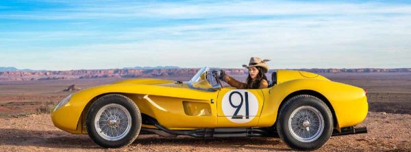 The Girl with the Feathered Hat, Monument Valley, Utah 2023, color by David Yarrow - Girl with a cowboy hat sitting in a yellow Car with the number 21 in the desert