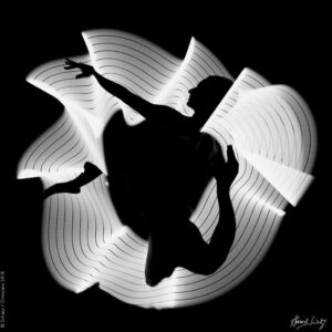 Light Study 1034 by Howard Schatz - abstract black and white image of a body and white strips of light looking like a flower
