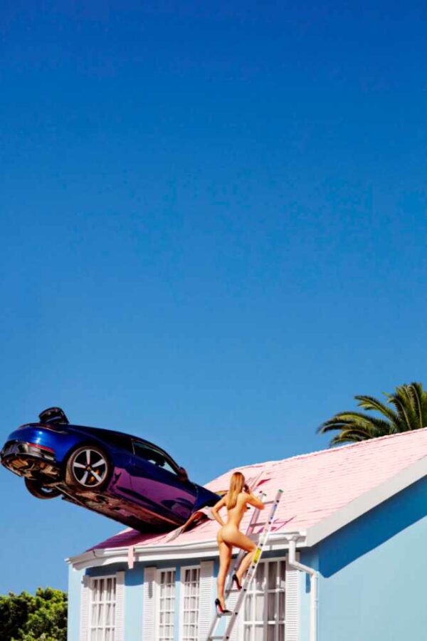 Rooftop Parking 2012 by Tony Kelly, purple porsche crashed into the pink roof of a blue house and a nude model in heels climbing up a ladder to